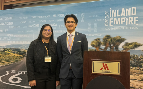 Chuong Ngyuen standing with another female student inside a conference room near a podium.