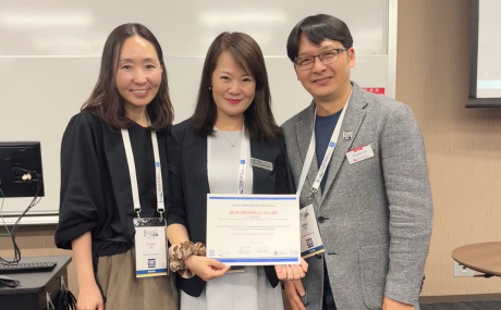 Wan Yang poses with certificate with two other professionals inside classroom.