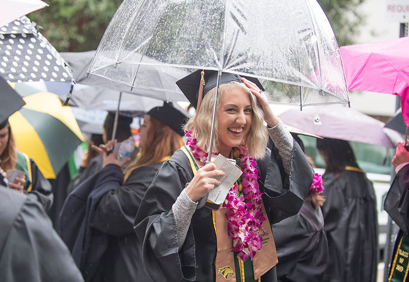 Female grad holding an umbrella in the rain
