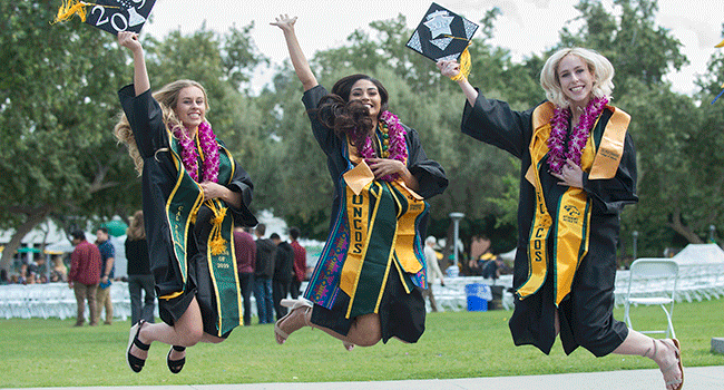 Three female graduates jump in celebration during the 2019 commencement ceremonies. 