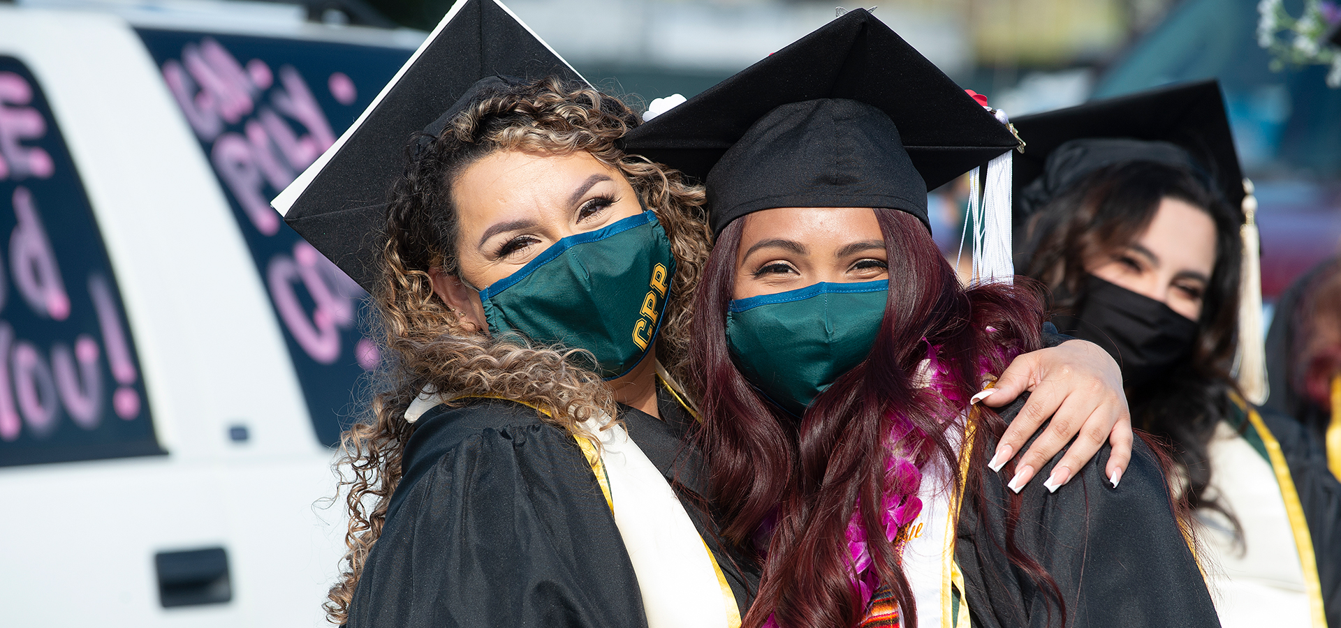 Two graduates hug and pose for a photo