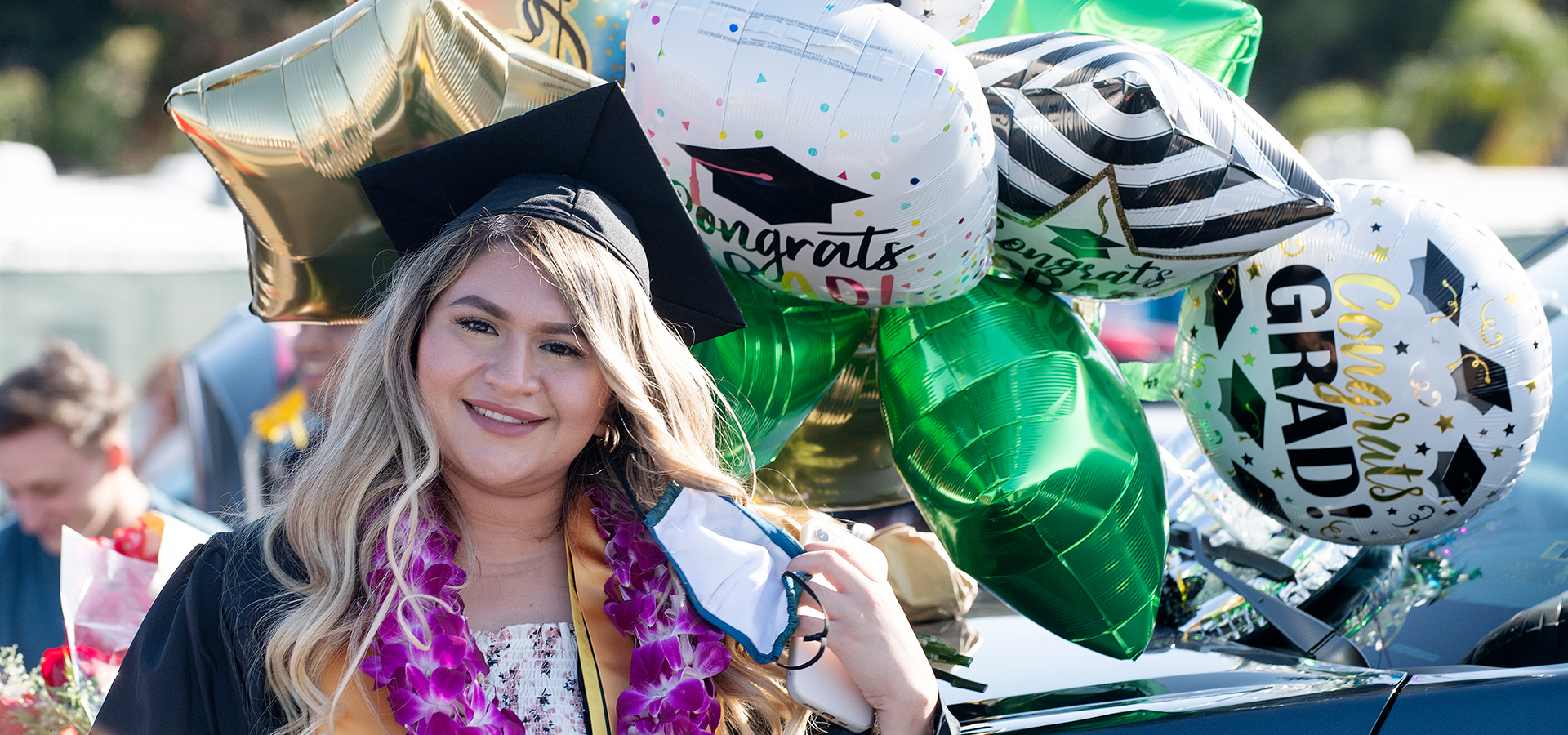 A graduate with a bouquet of balloons behind her
