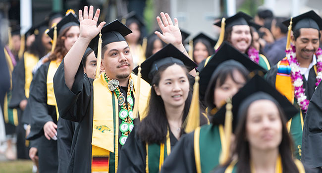 A male graduate waves to the crowd during commencement.