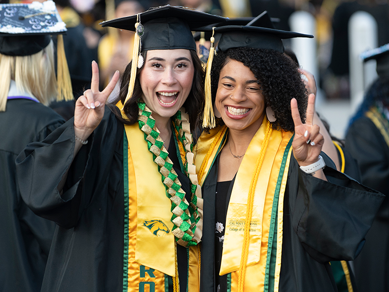 two female College of Ag students smile while giving the peace sign during the 2025 Commencement ceremonies.