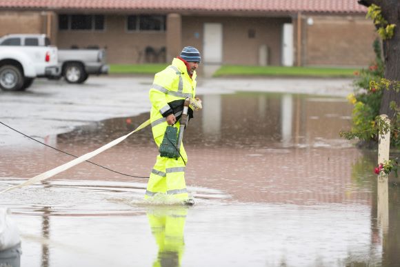 Facilities worker hauls pump to flooded section of horse center. 