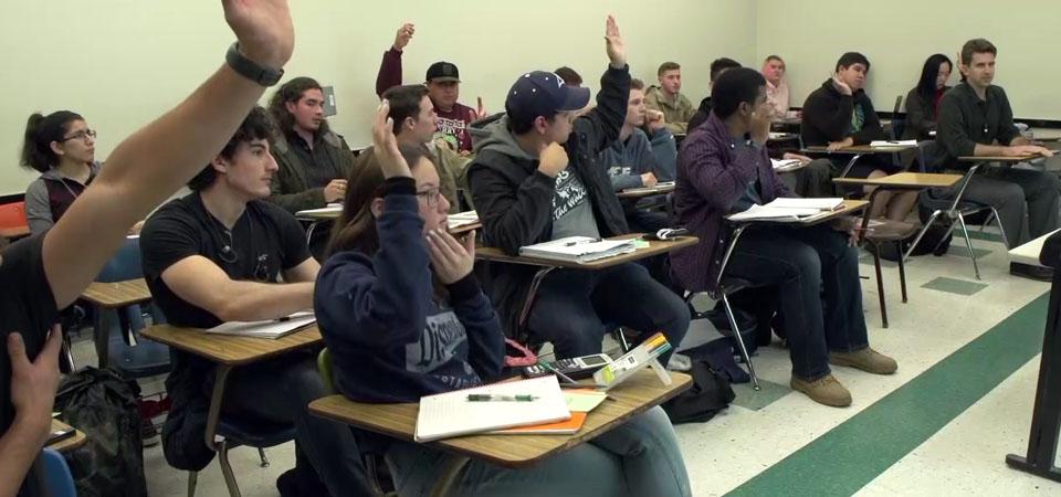 Students in Classroom raising their hands