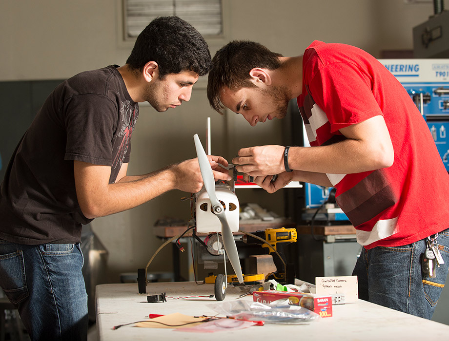 three people standing in front of a tech room wearing badges 