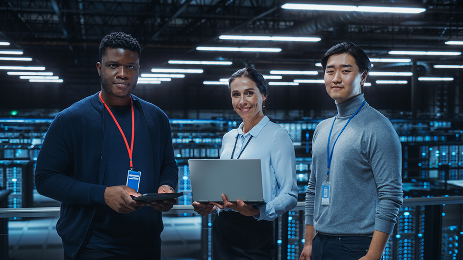 systems engineers standing in front of tech room holding laptop