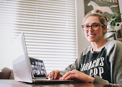student smiling while working on a laptop