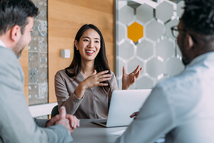 person with laptop in a meeting talking to two people