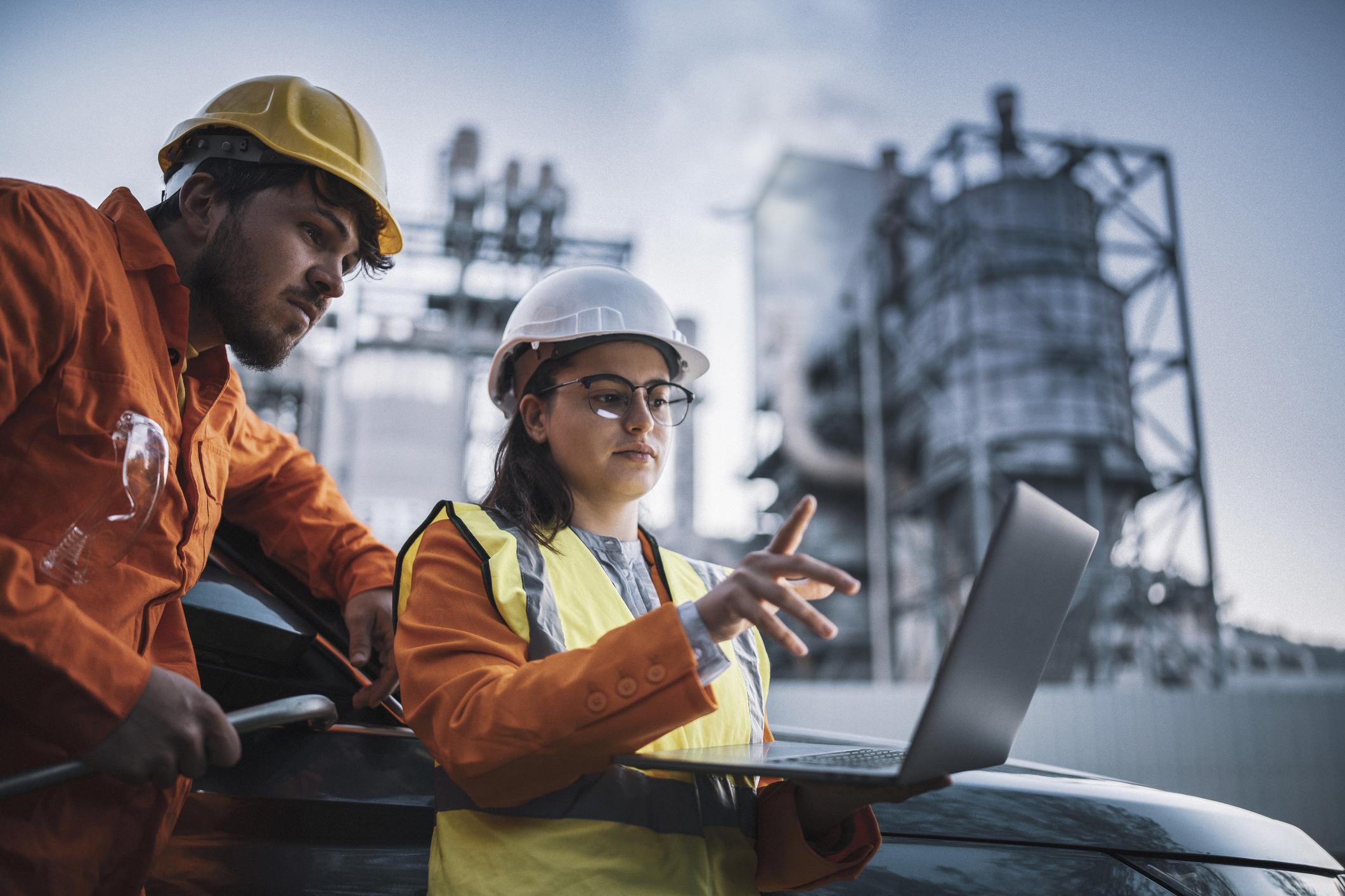 workers in safety equipment looking at laptop