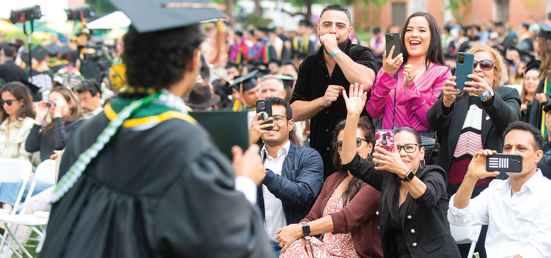 Male graduate's family taking photos as he crosses the stage