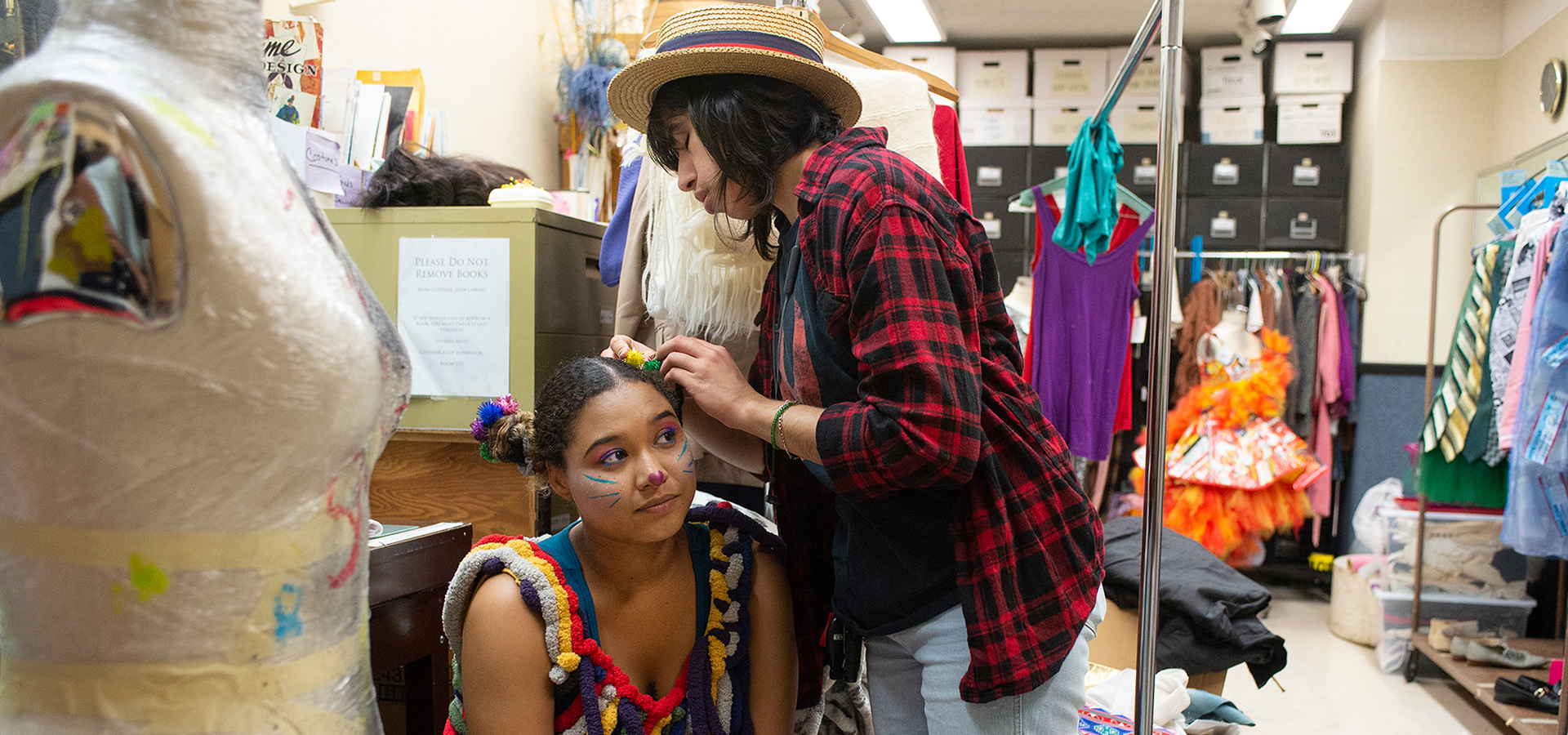 A female cast member helps with hair and makeup 