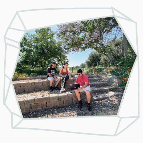 Three students sit in the outdoor classroom at the Lyle Center for Regenerative Studies.