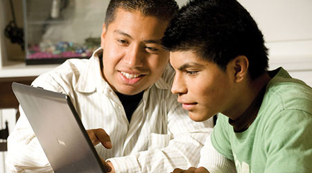 Enrique and Ramiro Montiel look at a laptop screen together.