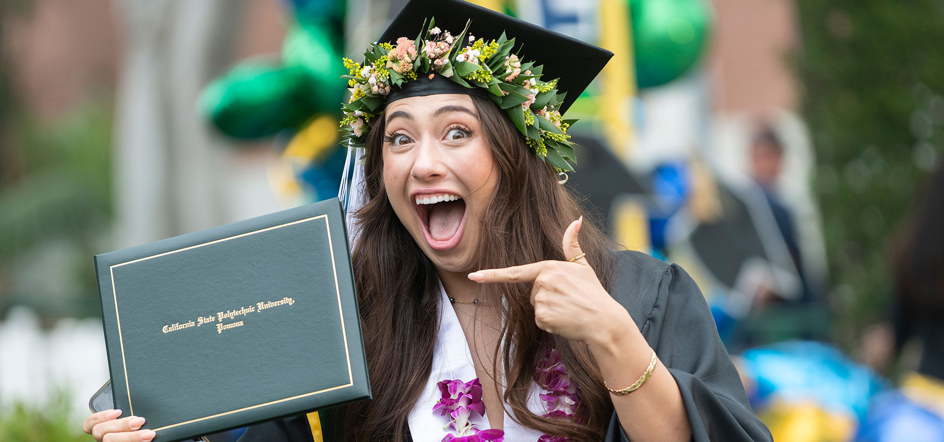 Female CLASS graduate smiles holding her diploma