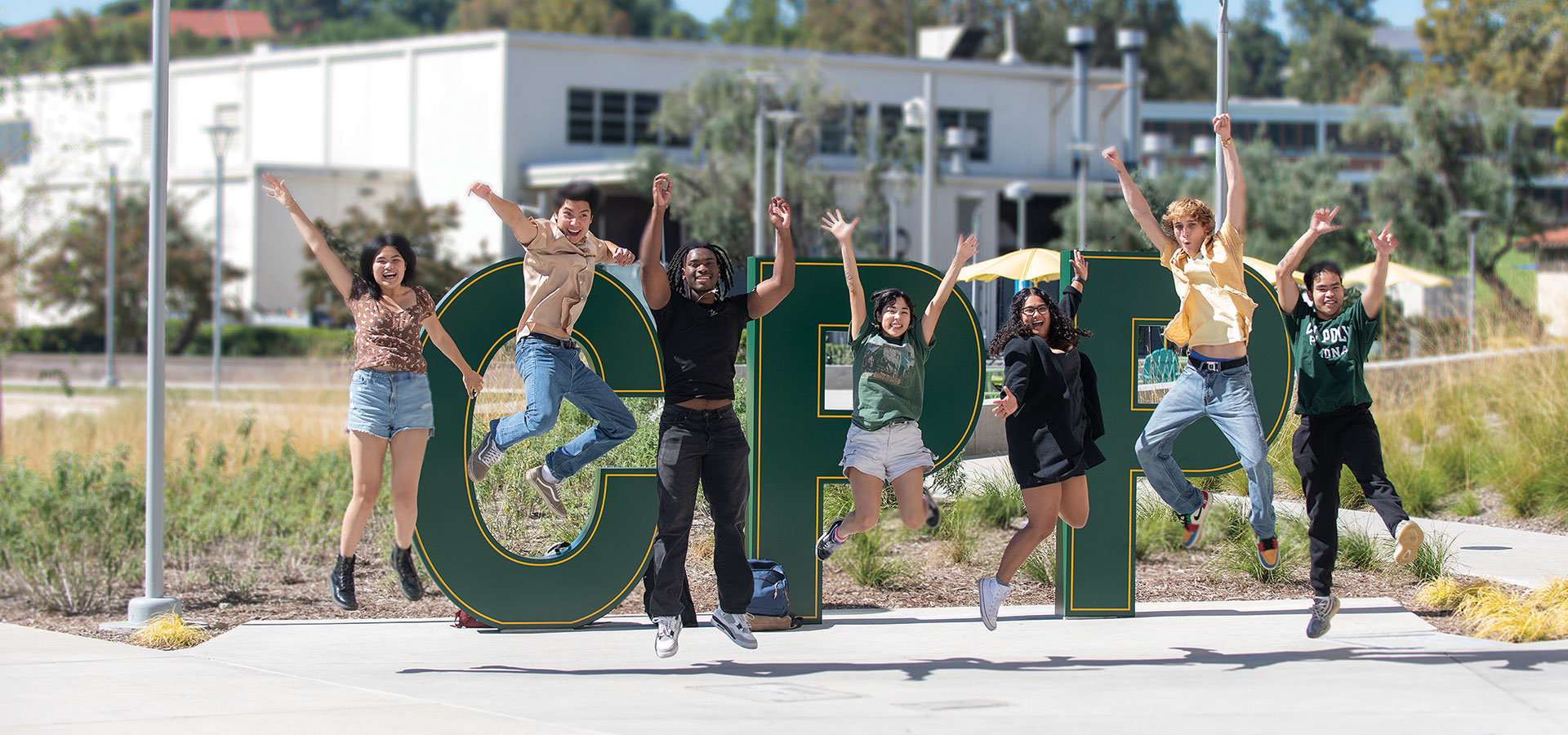 A group of students jump in celebration in front of the CPP letters at the Park at 98.