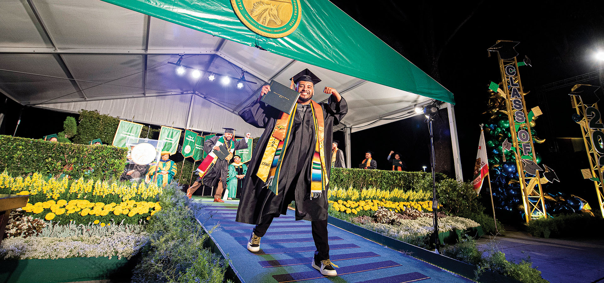 A male graduate celebrates as he walks down the commencement stage