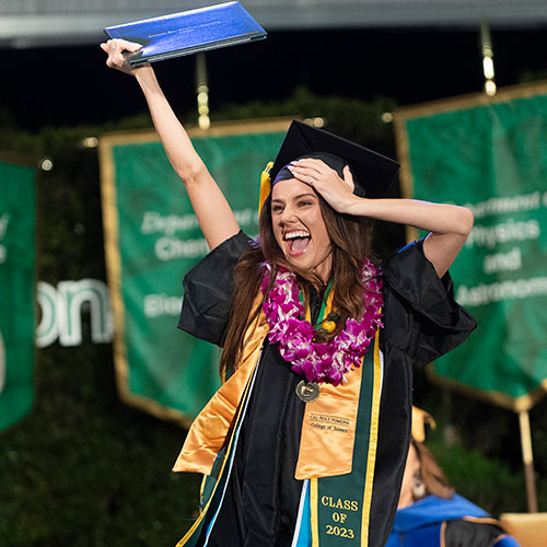 A female College of Science graduate holds her diploma on the commencement stage.