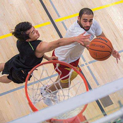 Two male students play basketball at the BRIC