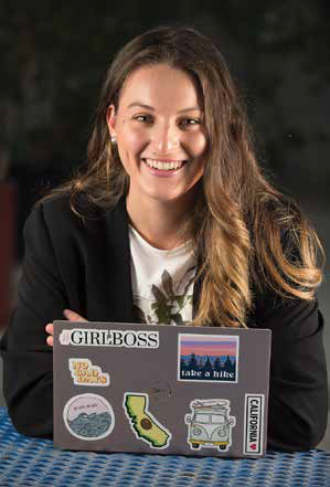 Isabel Gutierrez smiles while at a table with her laptop.