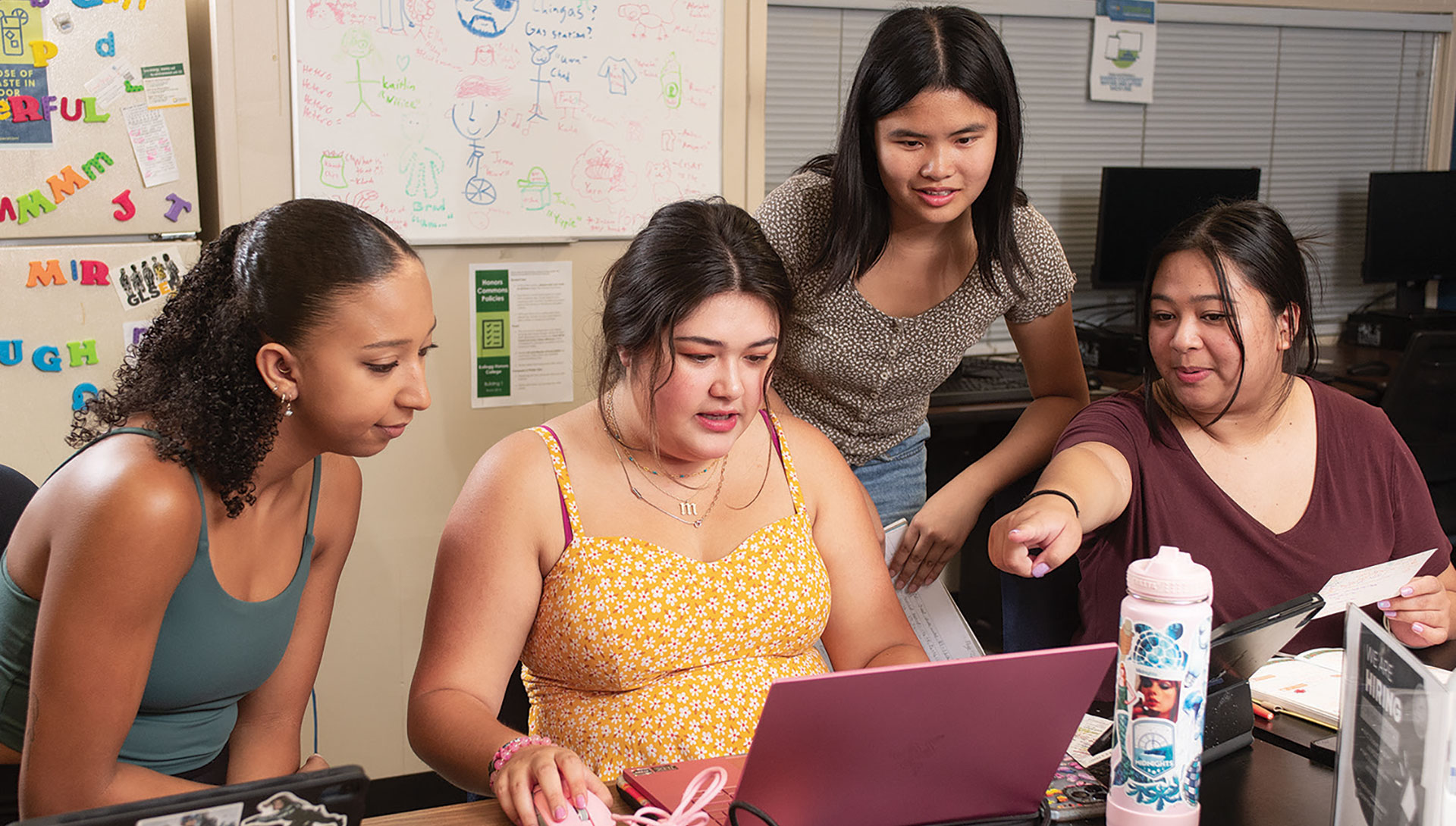 A group of female Kellogg Honors Students look at a laptop together.