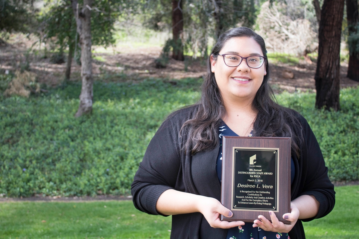 Awardee holding award in outdoors setting