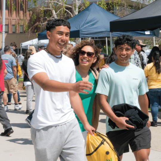 group of students walking by the CPP mural and a pair of prospective students with their parent