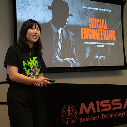 A student presents in front of screen projection that reads: Social Engineering