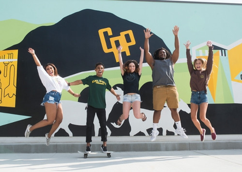 CPP students jumping in front of a mural on campus
