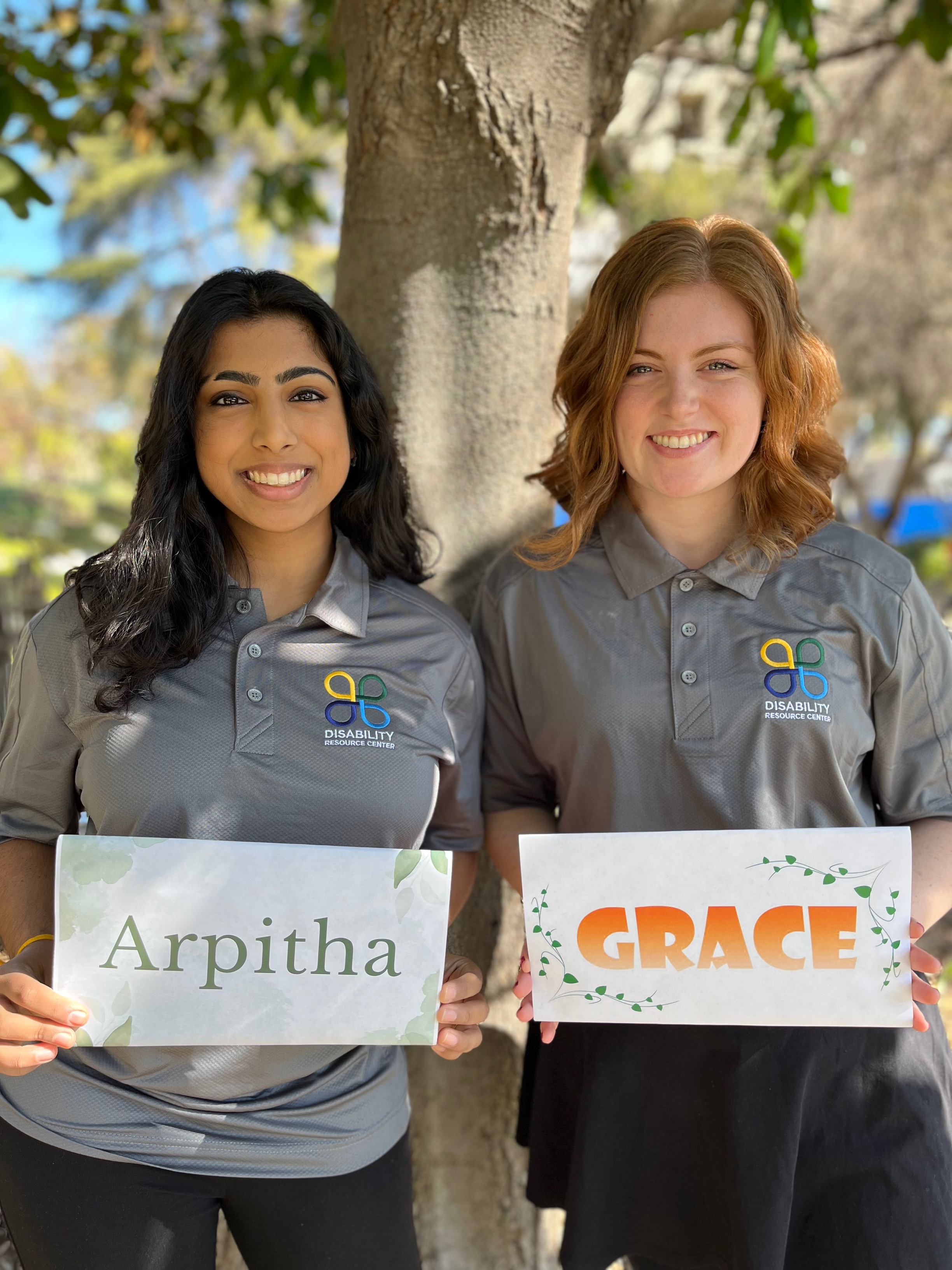 Access Mentors posing under a tree holding signs with their name