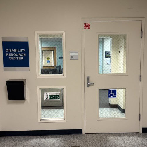 Entry door with blue sign with silver text and braille for Disability Resource Center