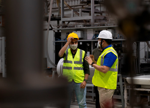 Two construction worker guys talking in work yellow safety jackets.