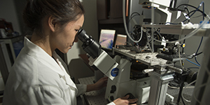 Woman looking through Microscope in Voss Lab