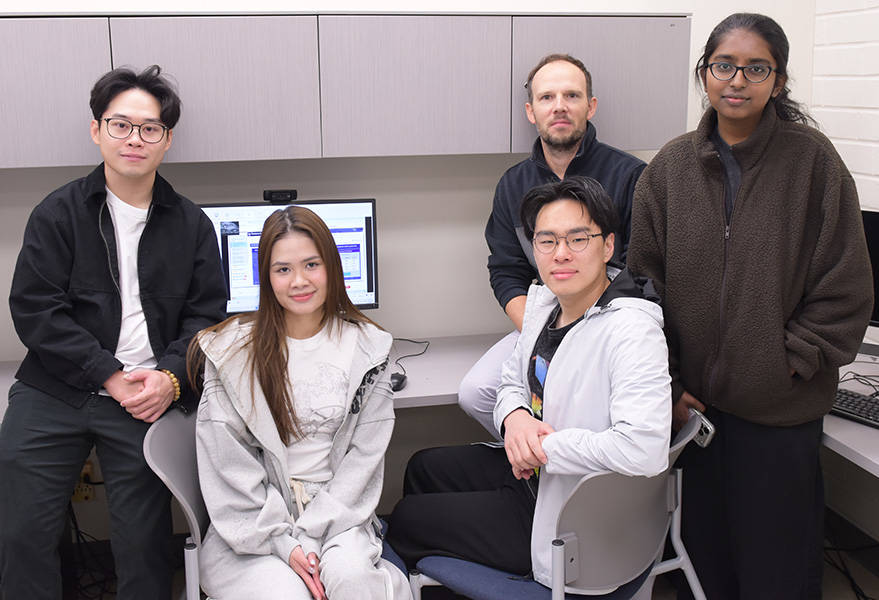 four students in a laboratory office with their professor