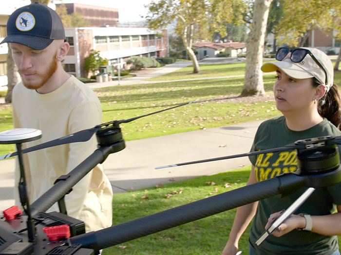 two students prepare to work with a drone on campus