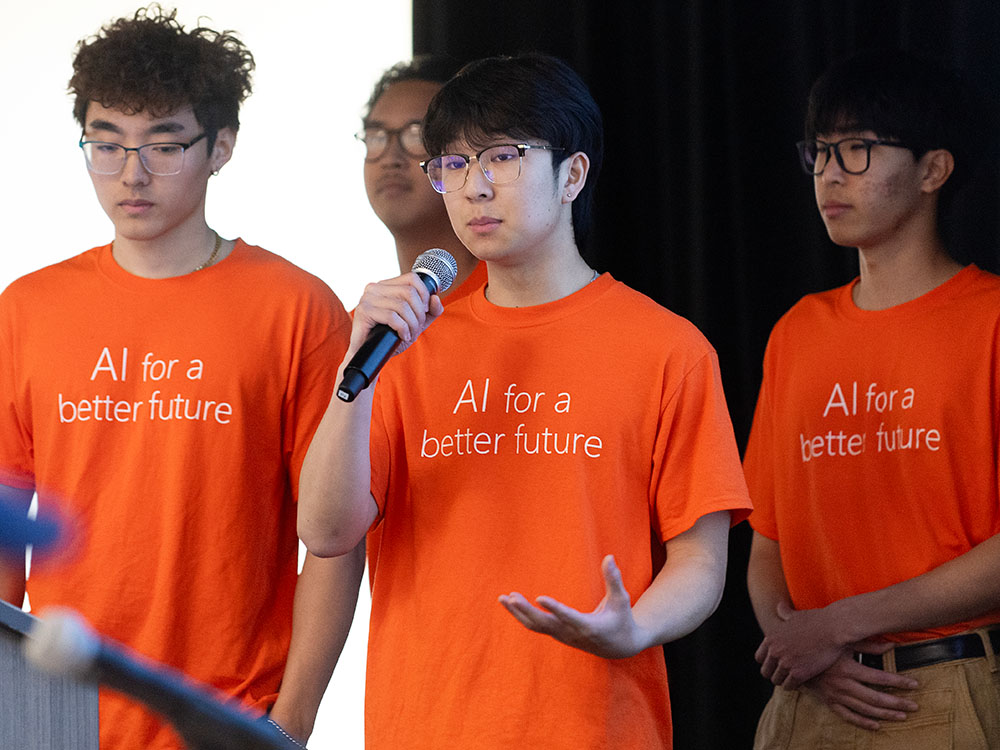 three students standing on stage