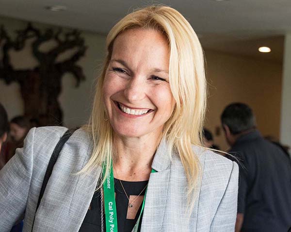 A blonde white woman in a grey blazer smiling at a students.