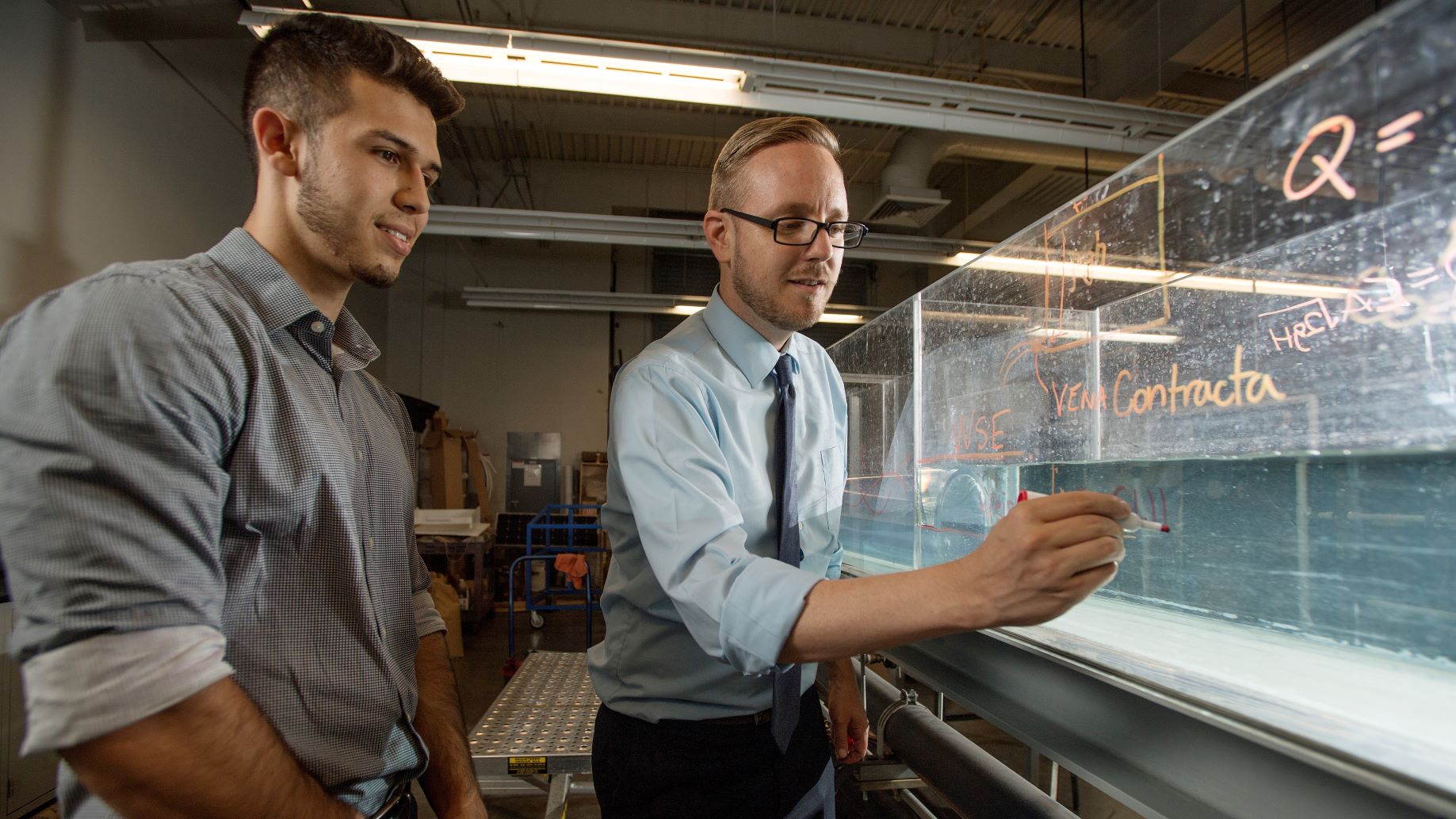 A civil engineering professor teaching a student in a hydraulics lab