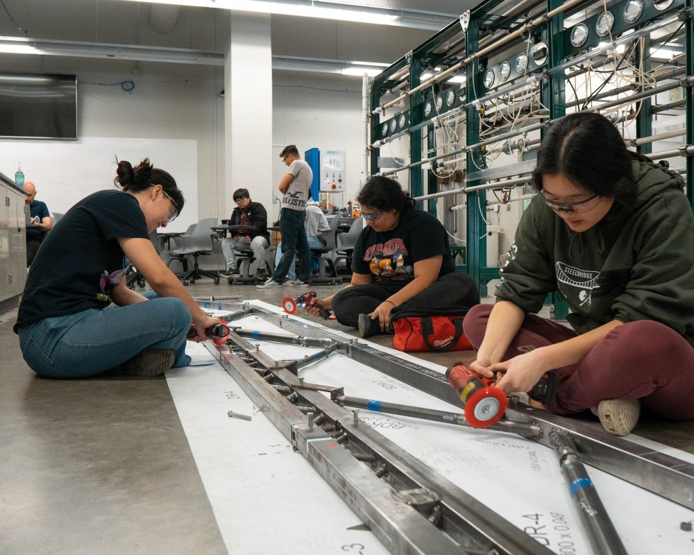 A group of engineering at Cal Poly Pomona assembling a steel bridge.