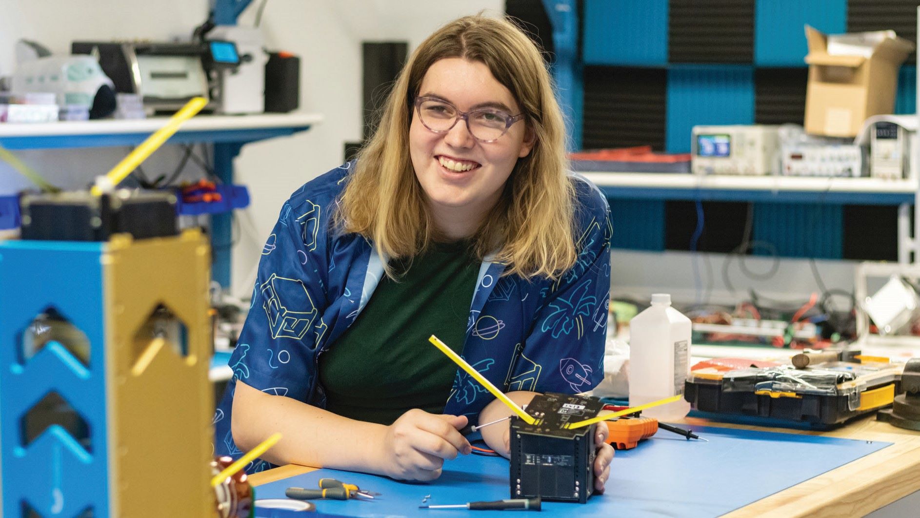 A female engineering student working on a CubeSat, a miniature satellite.