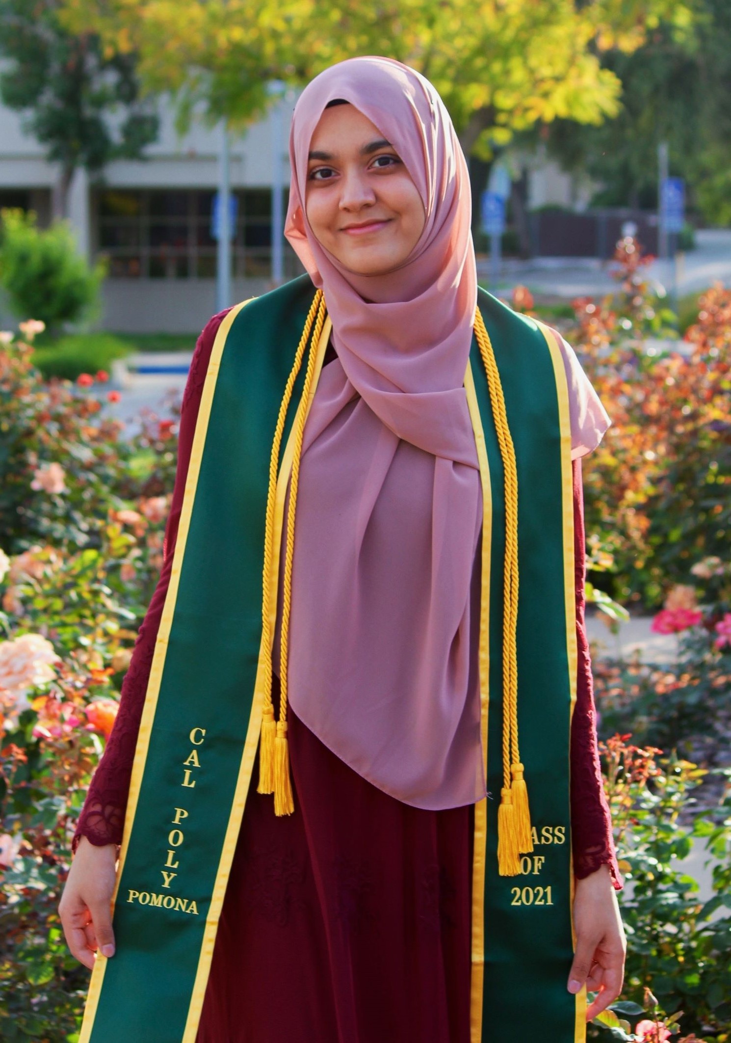 A female engineering student standing in front of a rose garden.