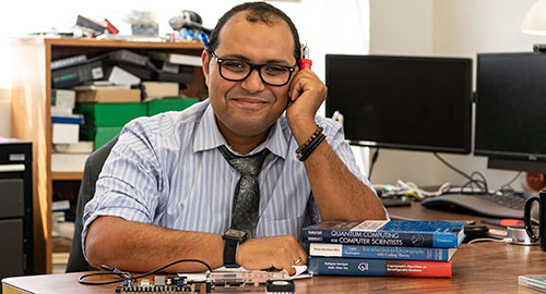A middle eastern CPP engineering professor with a stack of three books and computur hardware.