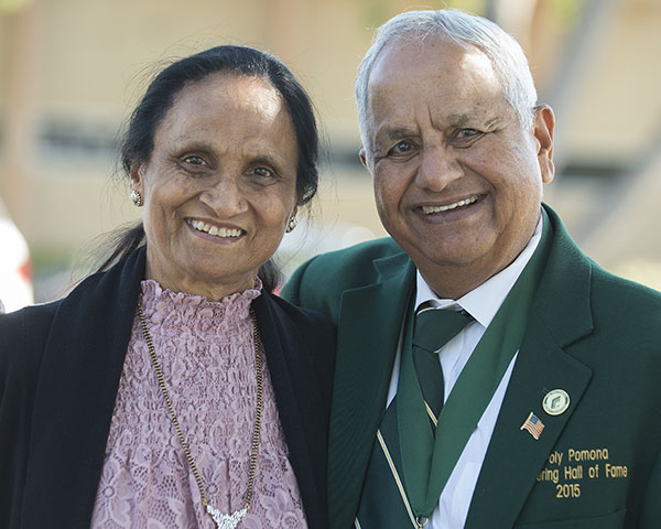 An engineering alumni with his wife. Both are smiling at the camera. The alumni has a green blazer with the embroidered text Cal Poly Pomona Engineering Hall of Fame 2015.