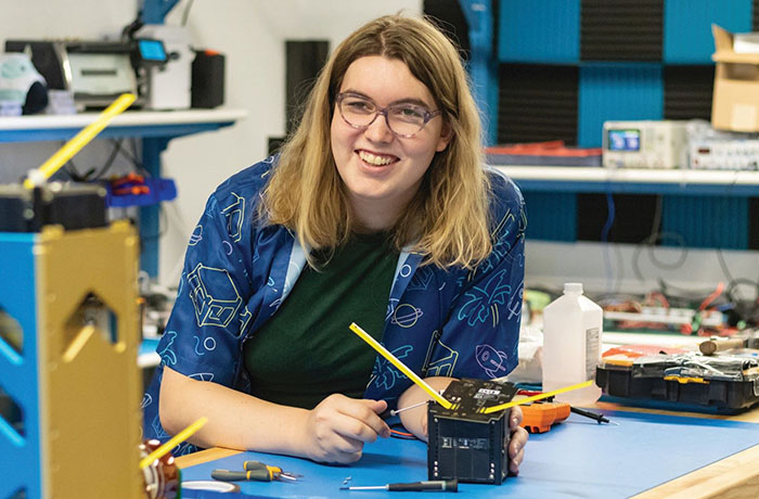 An engineering student working on a CubeSat.