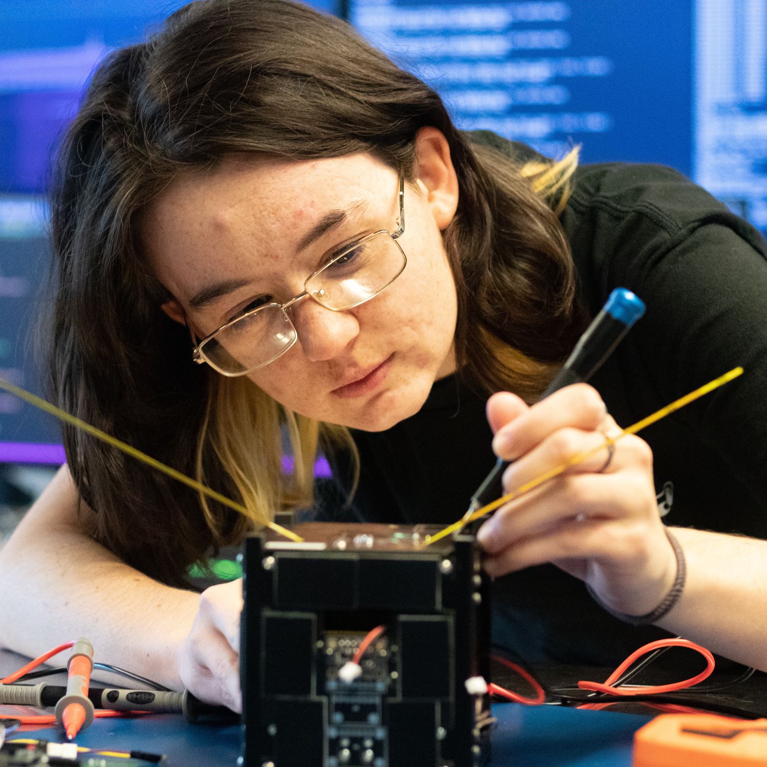 A female CPP College of Engineering student working on a CubeSat.