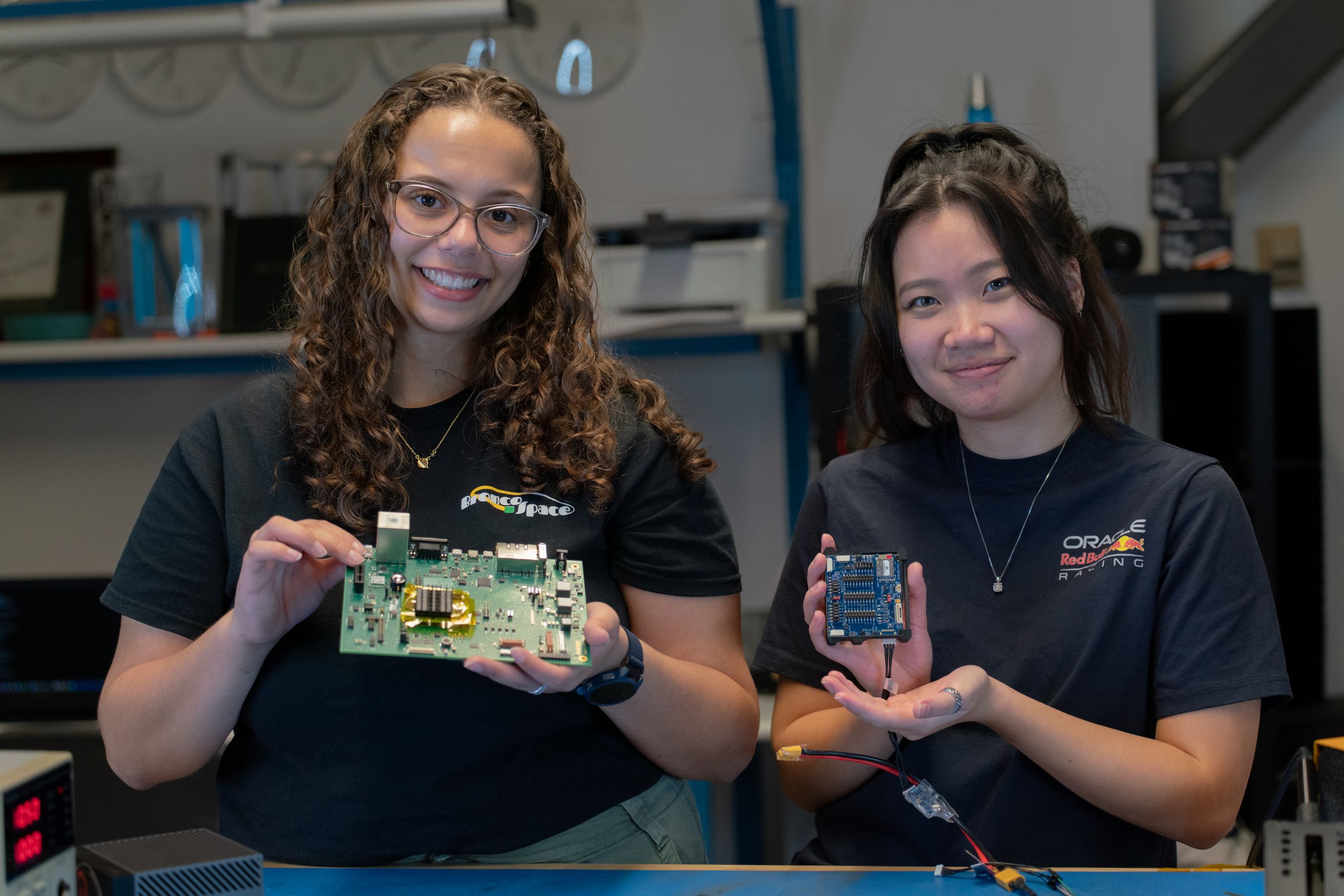 Two female engineering students at CPP College of Engineering holding their work in Bronco Space Lab.