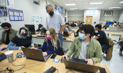 A middle-aged professor teaching his course to students in a classroom.