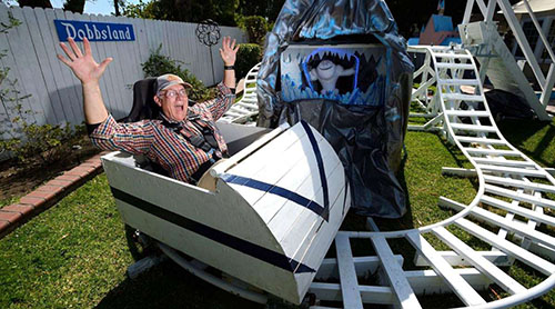 CPP College of Engineering professor Steve Dobbs on a miniature Disneyland rollercoaster he built in his backyard.