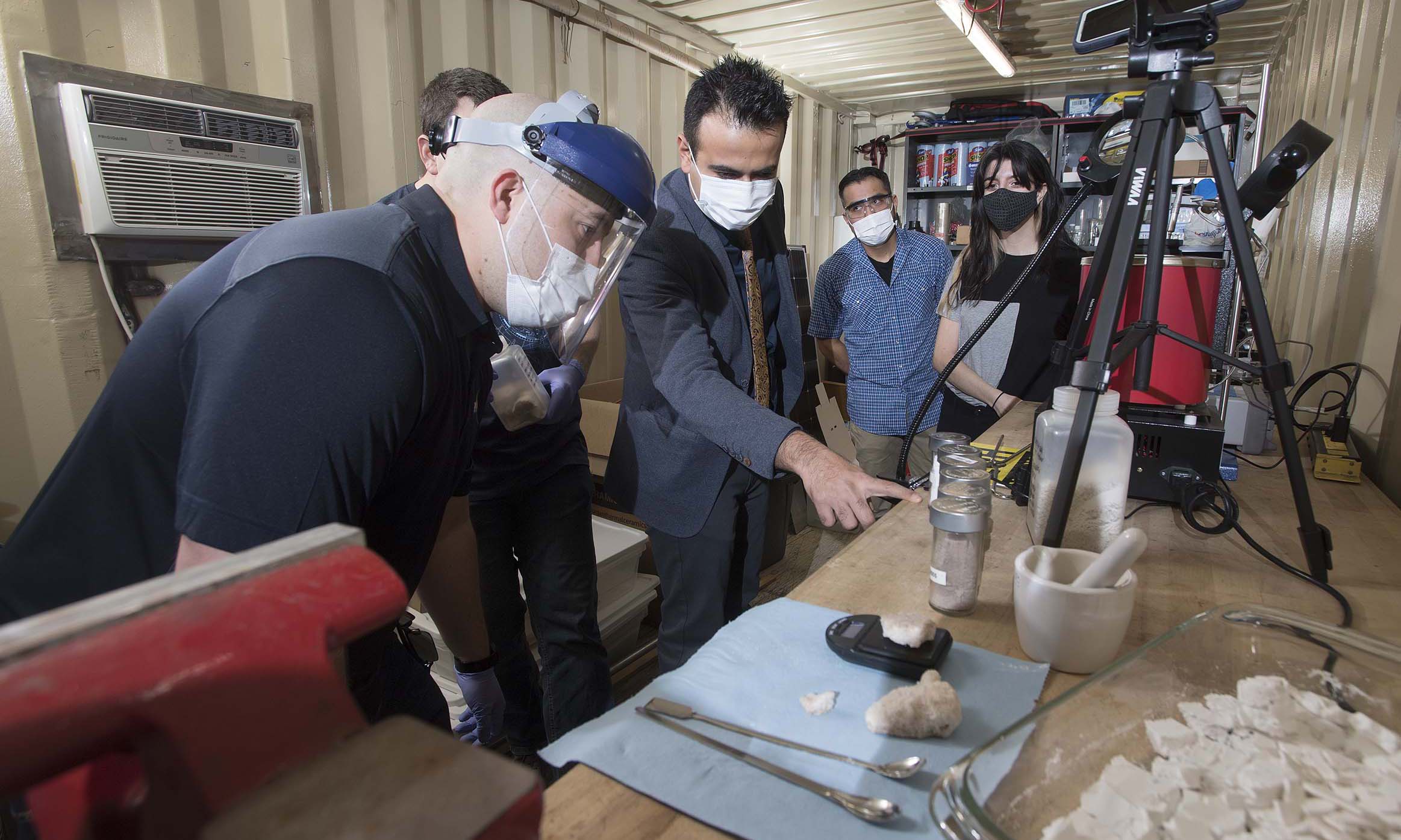 A male engineering professor providing instruction to four students in a research project.